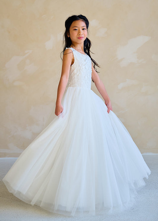 Shop the Elegant White Sleeveless Round Neck Communion Dress with Long Tulle Skirt, 3D Floral Plaque, and Tie in the Back - Perfect for Special Occasions!