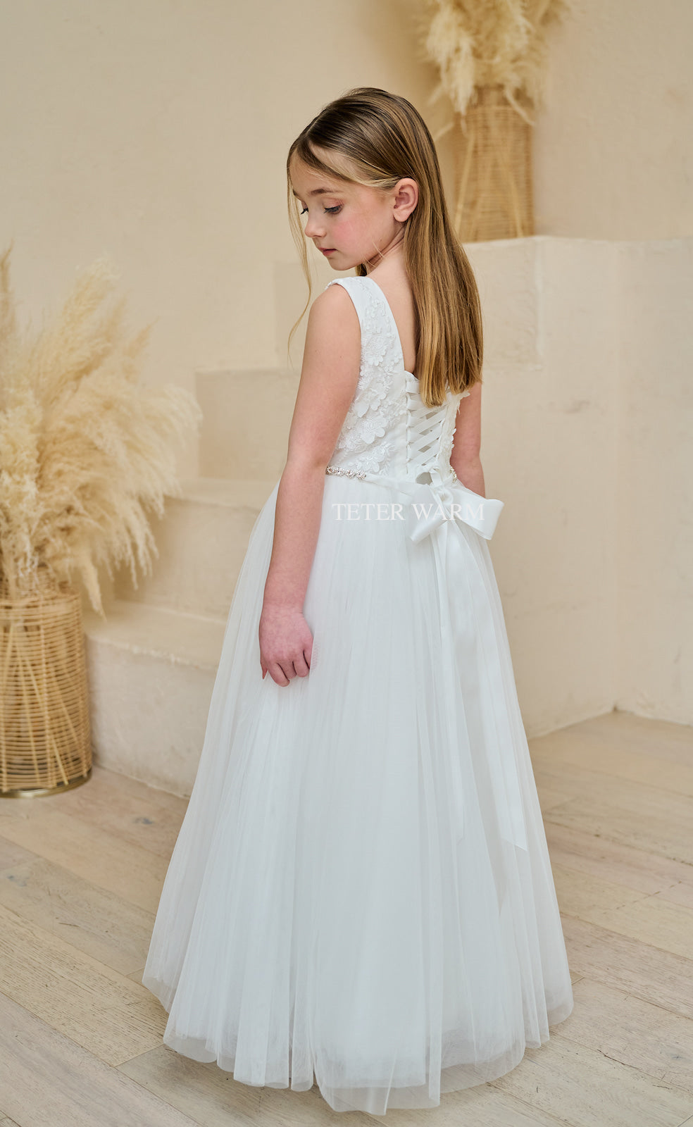 Shop the Elegant White Sleeveless Round Neck Communion Dress with Long Tulle Skirt, 3D Floral Plaque, and Tie in the Back - Perfect for Special Occasions!
